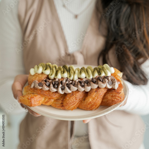 Young Beautiful Asian lady holds a plat with a twisted croissant.