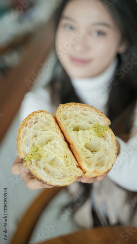 blur background of Beautiful Asian Girl with long hair, showing off Slice croissant, inside texture.