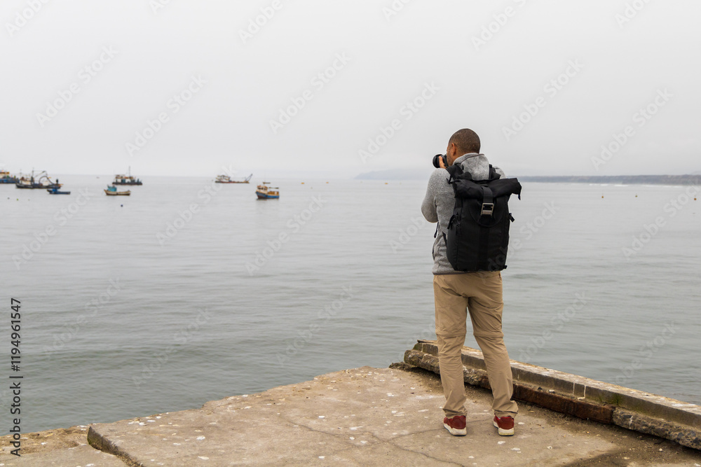 A man is taking a picture of the ocean with his camera A man is taking a picture of the ocean with his camera