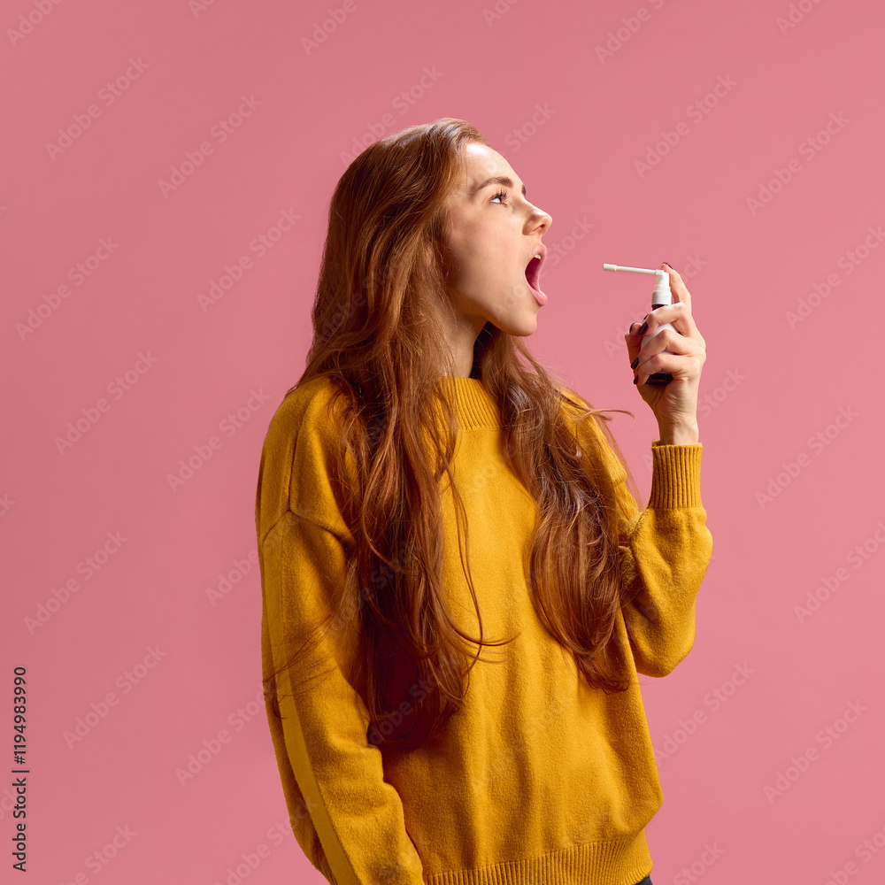 Obraz premium Side view image of young woman using throat spray on pink studio background. Treating viral infection, inflammation and irritation. Concept of illness, medicine, treatment, health care