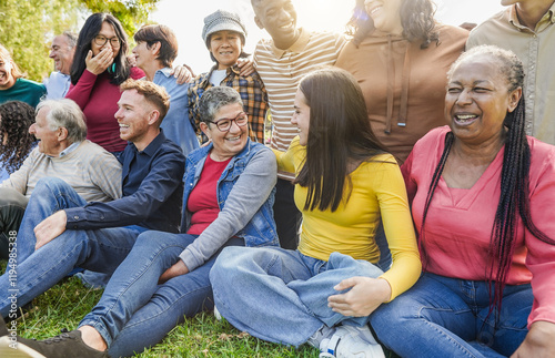 Group of multigenerational people chatting and enjoying time outdoor at city park - Multiracial friends of different ages having fun together - Main focus on woman with glasses