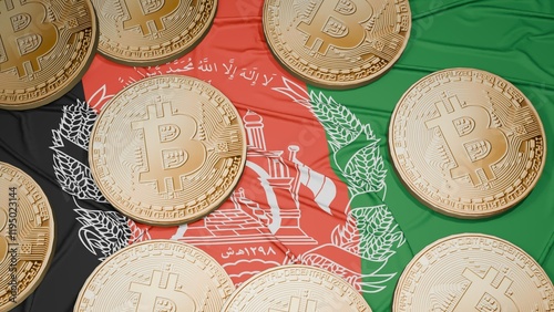 Several bitcoins are laid out on the flag of Afghanistan photo