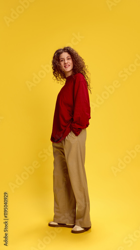 Charming young woman dressed casual attire, looking at camera cheerful smiling against sunny yellow studio background. Concept of human emotions, self-expression, fashion and style.