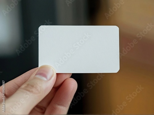 A person holding a blank card in a cozy indoor setting, with warm lighting and blurred background