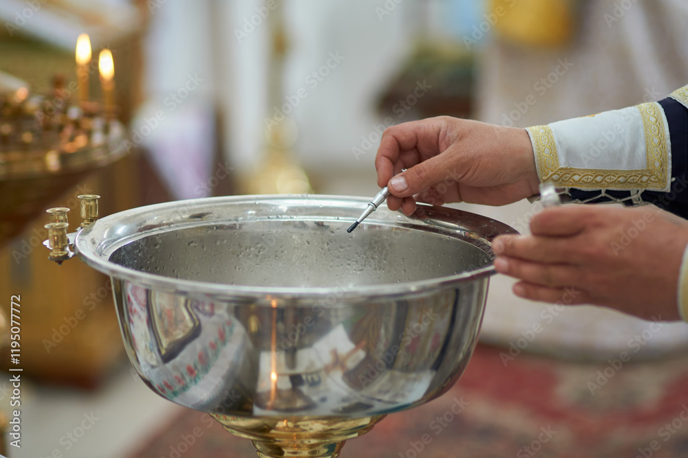 Photo of the process of consecration of water by the church priest during the ceremony of baptism of a child