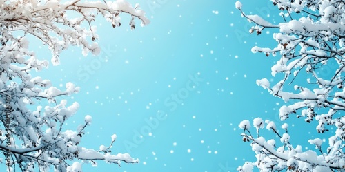 Snow-covered tree branches framing a vibrant blue sky with falling snowflakes and customizable blank space on the left for text placement. photo