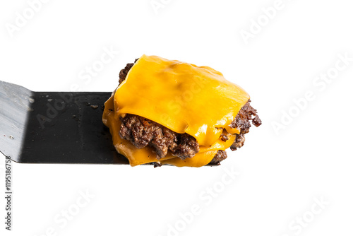 A juicy double patty topped with melted cheddar cheese on a stainless steel spatula, isolated on a white background photo
