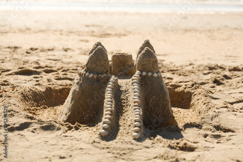 Sandburg mit Muschelverzierung am Strand