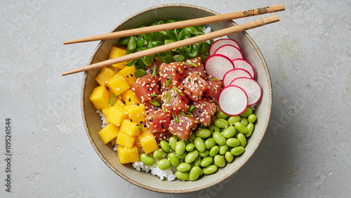 A colorful poke bowl with fresh tuna, mango, edamame, radishes, and sesame seeds served over rice.