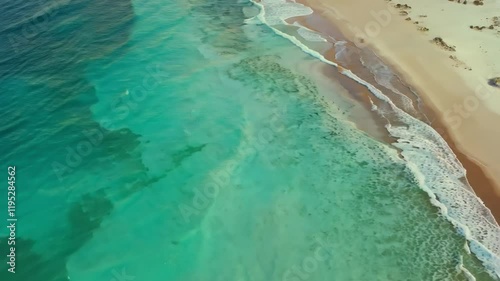 Aerial view of a serene beach with turquoise waters and gentle waves.