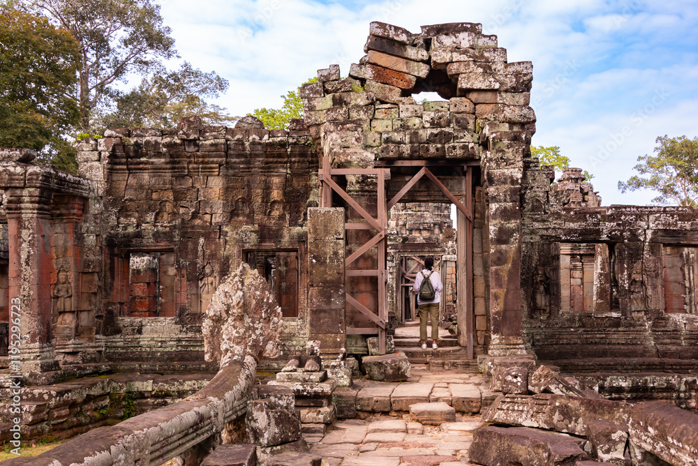 Naklejka premium Tourist entering Angkor ancient temple ruins in Cambodia