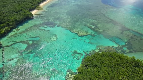 Aerial view of clear turquoise waters and coral reefs teeming with marine life.