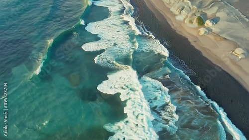 Aerial view of ocean waves crashing onto a sandy beach, showcasing vibrant blue waters.