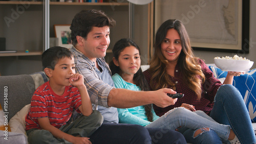 Family Sitting On Sofa Watching TV And Eating Popcorn Together