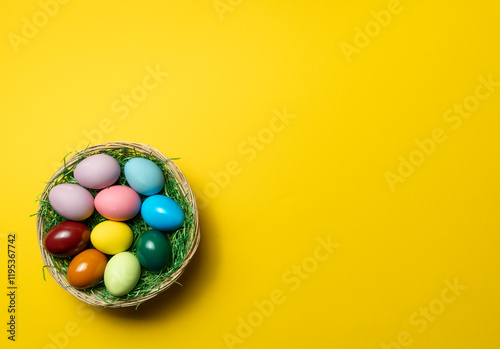 Easter eggs in nest on yellow background with space for text