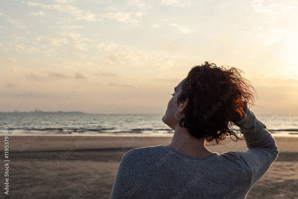 Portrait of a young woman with curly hair at sunset on the beach Portrait of a young woman with curly hair at sunset on the beach