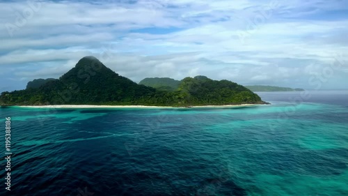 Aerial view of a lush, green island surrounded by vibrant turquoise waters and sandy beaches.
