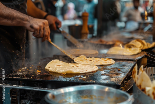 A chef flipping parathas on a hot griddle in a bustling street-side eatery photo