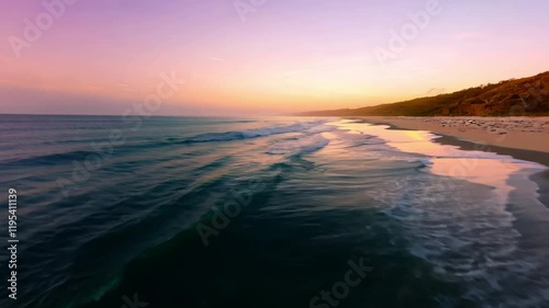 Serene beach at sunset with gentle waves and a lush coastline.
