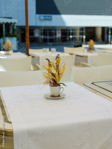 Fototapeta Naklejka Na Ścianę i Meble -  Gedeckter Tisch mit Trockenblumen in Straßencafé