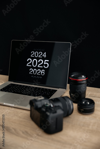 Selective focus on 2025 logo at displat. Laptop, camera and lenses - photographer's working tools photo