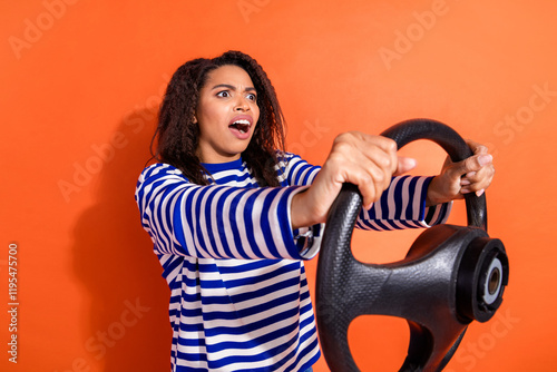 Photo of impressed shocked girl wear striped shirt riding car empty space isolated orange color background photo