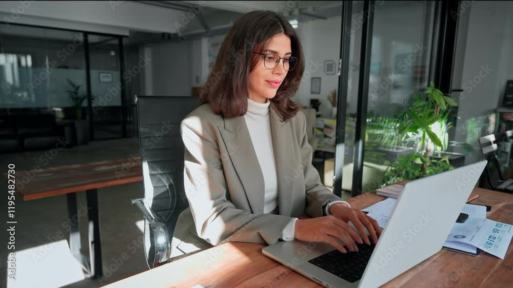 Young professional it specialist latin hispanic business lady working on laptop pc sitting at desk in modern office space. 30s middle eastern indian woman using computer technology app for work online