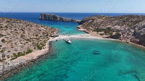 Aerial drone cinematic video of paradise two sided beach with crystal clear emerald sea in small islet of Kounoupa near Astypalaia island, Dodecanese, Greece photo