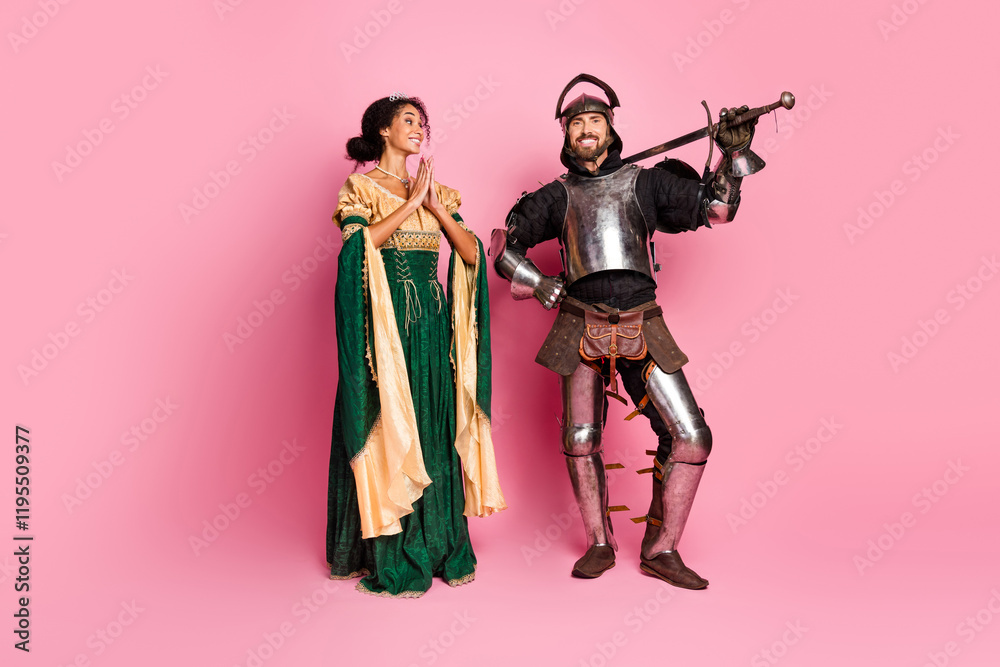 Charming couple dressed as medieval royalty in a knight's armor and a royal gown posing on a bright pink background Charming couple dressed as medieval royalty in a knight's armor and a royal gown posing on a bright pink background