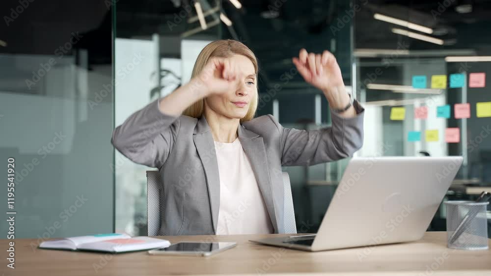 Happy businesswoman in a suit finished task on laptop sitting at desk at workplace in business office. Smiling satisfied female employee puts her hands behind her head, closed her eyes. Work done