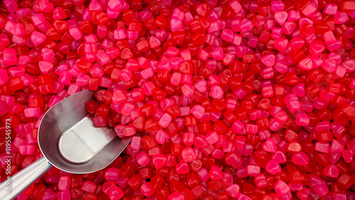 Bright red Jube heart candies with a metal scoop. Concept of heart, Valentine Day, sweetness, love, celebration, sweet treats. photo