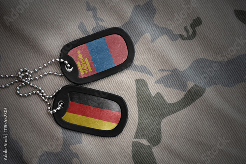 vintage army blank, dog tag with flag of mongolia and germany on the khaki texture background. military concept. photo