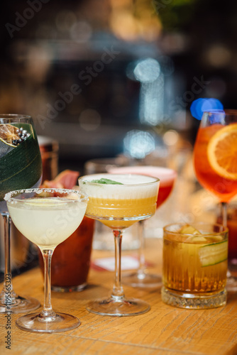 Сolorful cocktails close-up in elegant glassware, garnished with fruits and herbs, captured with a shallow depth of field for bokeh effect. Bright indoor bar setting, vertical image