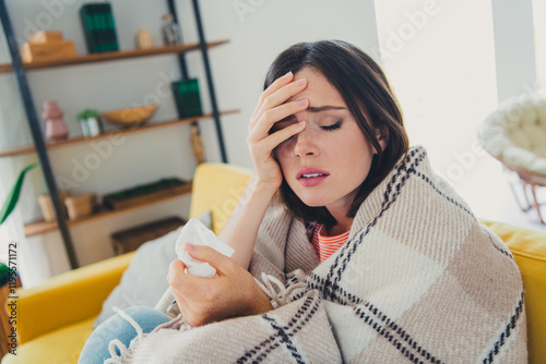 Young woman feeling unwell on a cozy couch at home indoors during the day