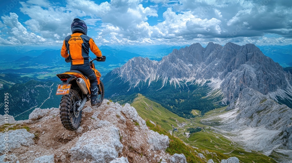 Fototapeta premium Motorcyclist on mountaintop overlooking valley.