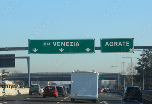 Highway sign for the slip road to the town of AGRATE near Milan in Italy or continue straight towards VENICE photo