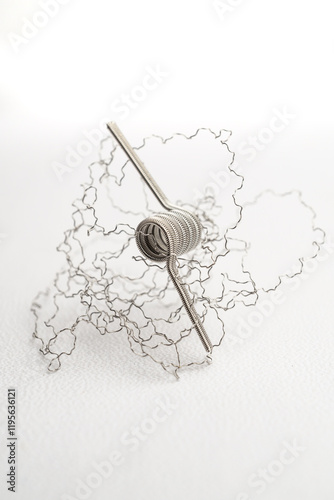 macro close up photo of vaping vaporizer single coil wire alien core coil, twisted messes coil in aluminum stainless steel on white background photo