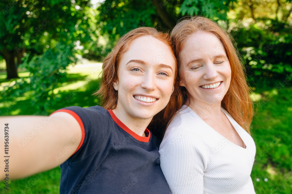 Smiling red-haired women take a selfie in a sunny green park on a bright afternoon Smiling red-haired women take a selfie in a sunny green park on a bright afternoon