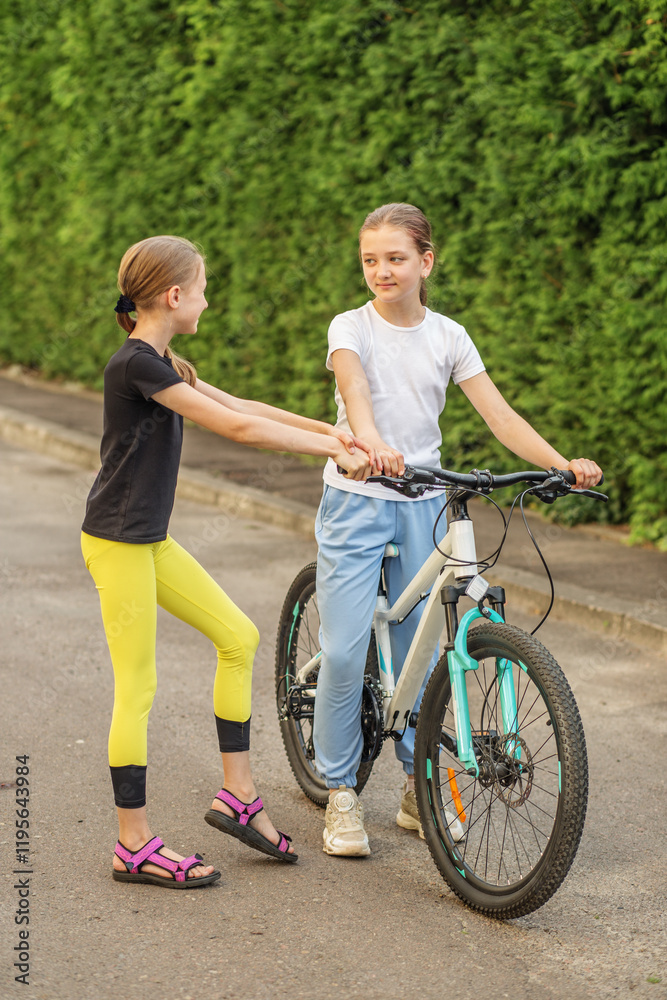 Preteens enjoying sunny afternoon while riding bikes in park Preteens enjoying sunny afternoon while riding bikes in park