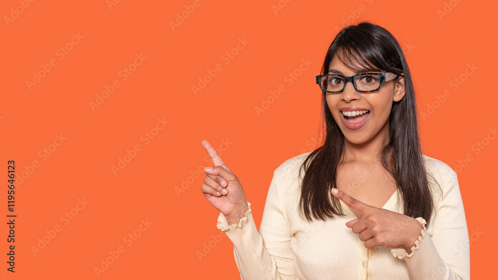 Engaging young woman gestures joyfully against a bright orange background Engaging young woman gestures joyfully against a bright orange background