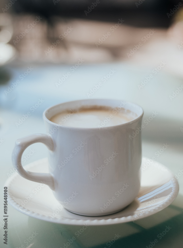 Delicious cappuccino coffee served in a white cup on a glass table. Delicious cappuccino coffee served in a white cup on a glass table.