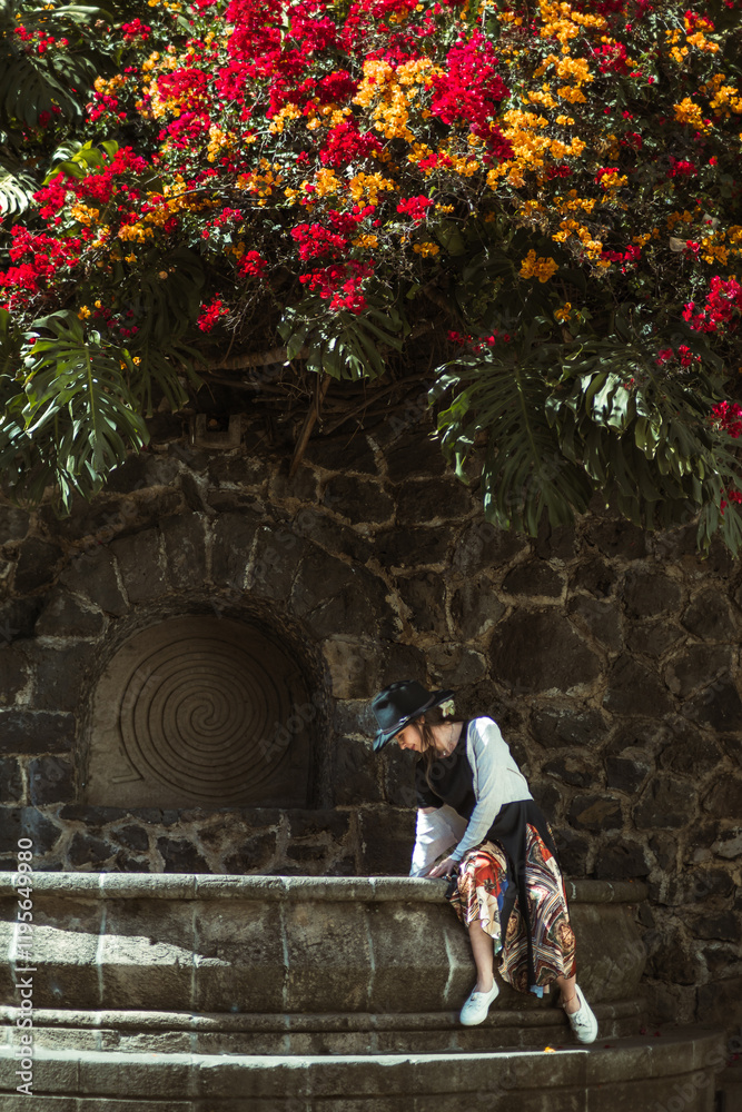 Fototapeta premium Girl sitting in a stone fountain playing with water, located in a magical town called Malinalco, State of Mexico.