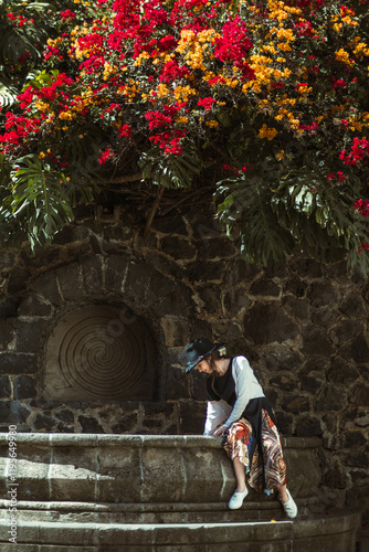Girl sitting in a stone fountain playing with water, located in a magical town called Malinalco, State of Mexico.
