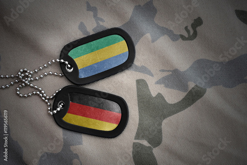 vintage army blank, dog tag with flag of gabon and germany on the khaki texture background. military concept.