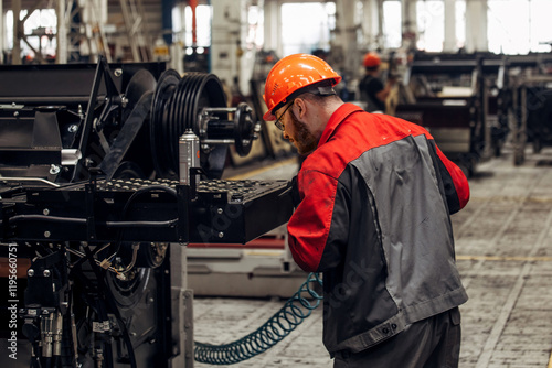 Foto Industrial worker assembles agricultural machine in workshop