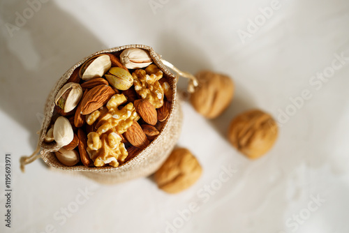 Mix of different nuts in a burlap sack. Jewish holiday Tu Bishvat concept on white background with copy space photo