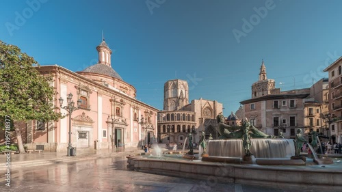 Panorama showing timelapse of Valencia's Plaza de la Virgen, showcasing Turia Fountain, Cathedral and Basilica de la Virgen de los Desamparados in Spain's historic old town under a blue sky photo