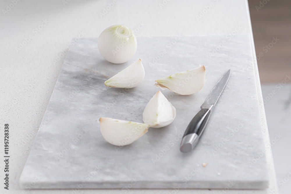 Fototapeta premium A white onion cut into quarters. A knife lies nearby
