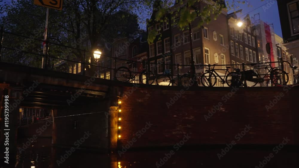 Cruising along a canal toward a brick bridge with trees and bicycles at night Cruising along a canal toward a brick bridge with trees and bicycles at night