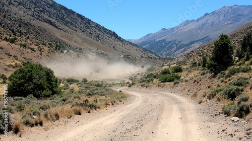 Dusty mountain road curves, vehicle dust cloud, arid landscape, travel photo